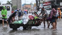 Seorang pria mendorong gerobak kayu yang membawa putrinya di sepanjang jalan yang terendam banjir setelah Topan Fung-wong. Foto: REUTERS/Noel Celis