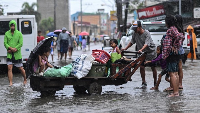 A man pushes a wooden cart carrying his daughters along a flooded street after Typhoon Fung-wong hit Dagupan City, Pangasinan, Philippines, November 10, 2025. REUTERS/Noel Celis