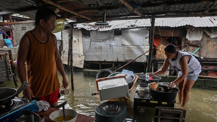 Evelyn Salvador, 49, washes the dishes outside her flooded house after Typhoon Fung-wong hit Dagupan City, Pangasinan, Philippines, November 10, 2025. REUTERS/Noel Celis