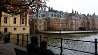 Orang-orang duduk di bangku menikmati pemandangan dekat Dewan Perwakilan Rakyat, Den Haag. REUTERS/Piroschka Van De Wouw  
