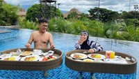 Pasangan suami istri yang harmonis ini juga kerap tampak mesra. Ini momen liburan mereka di Bali dan menikmati floating breakfast di sebuah resort. Foto: Instagram/@astridkuya