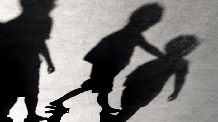 Two school kids fight in a dark passageway of their school, almost silhouette.