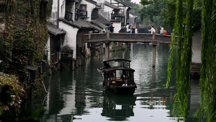 A person rides on a boat along a river at Wuzhen town of Tongxiang city, Zhejiang province, China November 8, 2025. REUTERS/Tingshu Wang