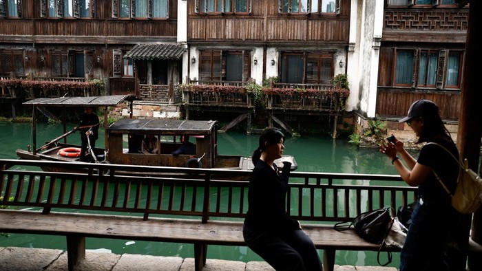 A person rides on a boat along a river at Wuzhen town of Tongxiang city, Zhejiang province, China November 8, 2025. REUTERS/Tingshu Wang