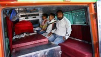 Seorang pria tampak duduk lemah di samping jenazah kerabatnya, sementara yang lain menunggu dengan wajah penuh duka di dalam ambulans. REUTERS/Anushree Fadnavis