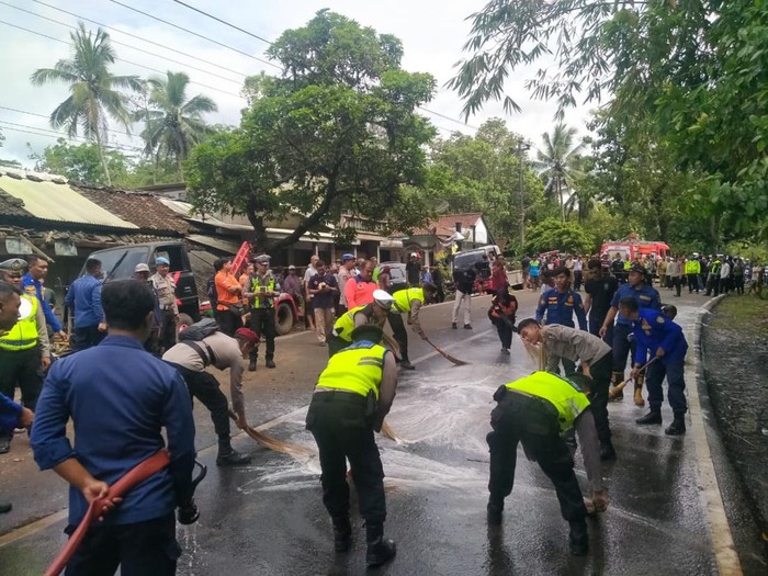 Polisi saat membersihkan tumpahan solar akibat kecelakaan maut di Jalan Purworejo–Magelang di depan Pasar Kalijambe, Desa Kalijambe, Kecamatan Bener, Kabupaten Purworejo, Selasa (11/11/2025).
