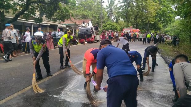 Polisi saat membersihkan tumpahan solar akibat kecelakaan maut di Jalan Purworejo–Magelang di depan Pasar Kalijambe, Desa Kalijambe, Kecamatan Bener, Kabupaten Purworejo, Selasa (11/11/2025).