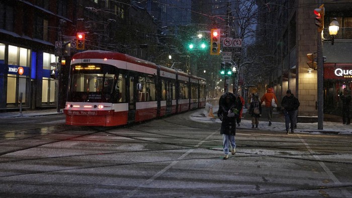 People walk next to a vehicle with its windshield covered with snow, as the season's first snowfall blankets the city, in downtown Toronto, Ontario, Canada, November 9, 2025. REUTERS/ Wa Lone