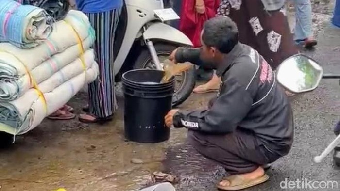 Warga berebut solar dari tumpahan truk tangki saat laka di Kalijambe, Purworejo, Selasa (11/11/2025).