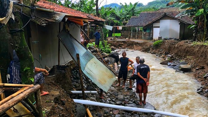 Warga memeriksa bangunan yang tergerus aliran sungai usai banjir di Desa Cidadap, Kecamatan Simpenan, Kabupaten Sukabumi. Sebagian pondasi rumah hilang terbawa arus.