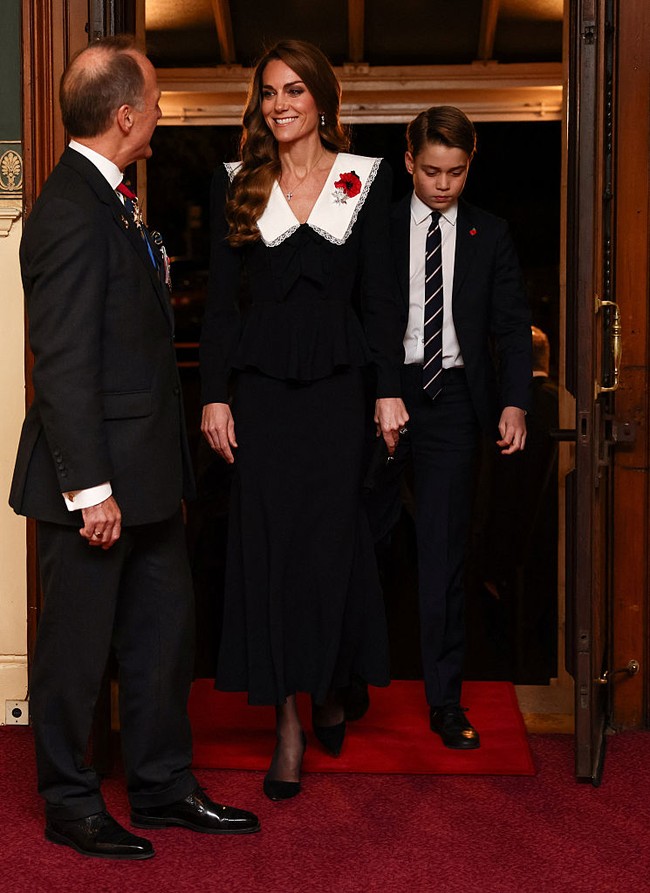 Kate Middleton tampil anggun mengenakan dress hitam berkerah rancangan Alessandra Rich. Pangeran George tampak berwibawa menyapa para tamu dan memberi penghormatan bersama anggota kerajaan lainnya, termasuk Raja Charles III. Foto: Getty Images/WPA Pool