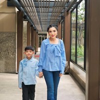 Ashanty memilih blus biru muda berdetail pita besar di bagian dada, memberi kesan lembut dan elegan. Potongan bahunya yang sedikit terbuka membuat tampilannya feminin namun tetap sopan. Ia memadukannya dengan celana jeans lurus berwarna senada, menciptakan tampilan kasual yang tetap chic. Foto: Instagram/@ashanty_ash