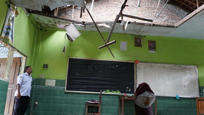 Seorang guru melihat atap ruang kelas ambruk di Sekolah Dasar Negeri Plosogenuk 1, Kecamatan Perak, Kabupaten Jombang, Jawa Timur, Rabu (12/11/2025). Sebanyak 60 siswa kelas VI terpaksa belajar di parkiran, ruang Perpustakaan dan UKS disebabkan atap ruang kelas ambruk. ANTARA FOTO/Syaiful Arif