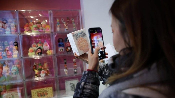 A staff member arranges some POP MART LABUBU THE MONSTERS dolls on a window shop ahead of an AliExpress and Pop Mart livestream shopping show on Singles' Day at a pop-up store in London, Britain, November 11, 2025. REUTERS/Isabel Infantes