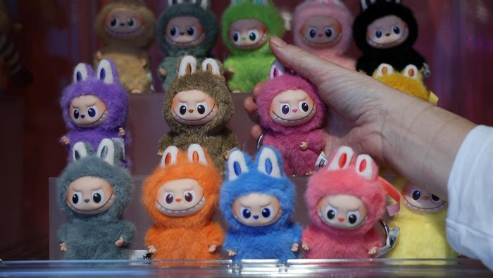 Boneka Labubu Bikin Heboh, Penjualan Melonjak Ribuan Persen A staff member arranges some POP MART LABUBU THE MONSTERS dolls on a window shop ahead of an AliExpress and Pop Mart livestream shopping show on Singles' Day at a pop-up store in London, Britain, November 11, 2025. REUTERS/Isabel Infantes