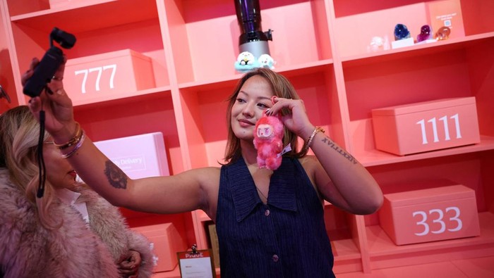 Boneka Labubu Bikin Heboh, Penjualan Melonjak Ribuan Persen A staff member arranges some POP MART LABUBU THE MONSTERS dolls on a window shop ahead of an AliExpress and Pop Mart livestream shopping show on Singles' Day at a pop-up store in London, Britain, November 11, 2025. REUTERS/Isabel Infantes