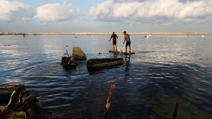 Palestinians look at crates of fish for sale, during a ceasefire between Israel and Hamas, at the seaport of Gaza City, November 12, 2025. REUTERS/Mahmoud Issa
