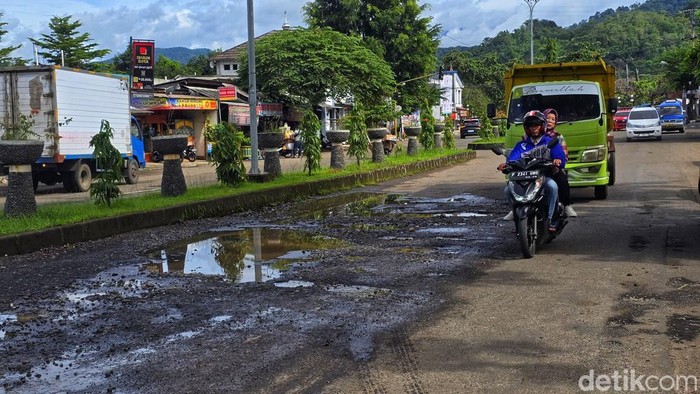 Kondisi Jalan Ahmad Yani di depan RSUD Palabuhanratu tampak rusak parah, dengan lubang dan genangan air yang membuat kendaraan melintas perlahan. Warga menyebut ruas ini sering menjadi langganan perbaikan setiap tahun.