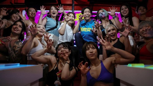Tomomi Matsumoto, 35, a staffer at Muscle Girls, a fitness-themed bar, lifts her shirt to show customers a tattoo on her torso in Tokyo, Japan, September 11, 2025. At 