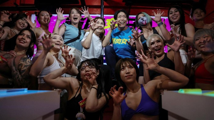 Tomomi Matsumoto, 35, a staffer at Muscle Girls, a fitness-themed bar, lifts her shirt to show customers a tattoo on her torso in Tokyo, Japan, September 11, 2025. At 