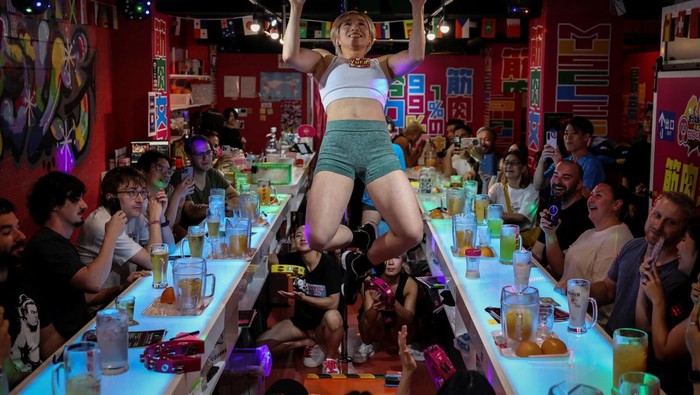 Tomomi Matsumoto, 35, a staffer at Muscle Girls, a fitness-themed bar, lifts her shirt to show customers a tattoo on her torso in Tokyo, Japan, September 11, 2025. At 