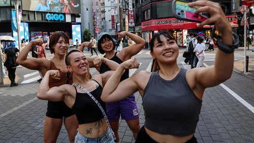 Tomomi Matsumoto, 35, a staffer at Muscle Girls, a fitness-themed bar, lifts her shirt to show customers a tattoo on her torso in Tokyo, Japan, September 11, 2025. At 
