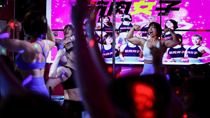 Tomomi Matsumoto, 35, a staffer at Muscle Girls, a fitness-themed bar, lifts her shirt to show customers a tattoo on her torso in Tokyo, Japan, September 11, 2025. At 