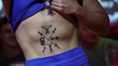 Tomomi Matsumoto, 35, a staffer at Muscle Girls, a fitness-themed bar, lifts her shirt to show customers a tattoo on her torso in Tokyo, Japan, September 11, 2025. At 