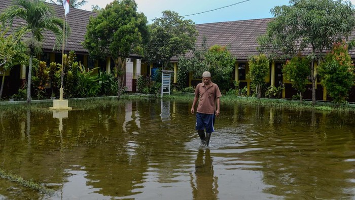 Penjaga sekolah membersihkan sisa banjir di SD Negeri Pamarican 2, Kota Serang, Banten, Kamis (13/11/2025). Sebanyak dua sekolah dasar di daerah tersebut terdampak banjir sejak Senin (10/11) akibat posisi sekolah yang lebih rendah dari jalan disertai buruknya saluran drainase sehingga mengakibatkan kegiatan belajar mengajar terpaksa dilaksanakan secara daring. ANTARA FOTO/Muhammad Bagus Khoirunas/bar