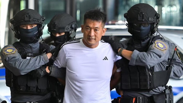 She Zhijiang, 43, a Chinese national gambling kingpin who was arrested by Thai police in August 2022 on an international warrant and an Interpol red notice requested by Beijing of having run illegal online gambling operations, is escorted by police ahead of being extradited to China, at Bangkok Suvarnabhumi Airport, in Samut Prakan, Thailand, November 12, 2025. REUTERS/Thanaphon Wuttison Purchase Licensing Rights