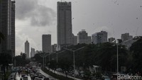 Warga melintasi pedestrian Jl Sudirman, Jakarta, menggunakan payung saat hujan deras, Kamis (13/11/2025).