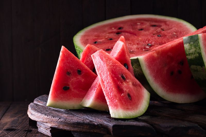 watermelon and watermelon pieces in a wooden background.