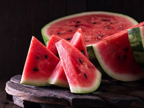 828468832 watermelon and watermelon pieces in a wooden background.