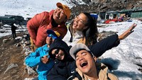 Angela Gilsha bersama teman-teman sependakian tertawa bahagia dengan panorama pegunungan bersalju. Everest Base Camp adalah dua lokasi perkemahan di kaki Gunung Everest. Ada Camp Selatan di Nepal dengan ketinggian 5.364 MDPL dan Camp Utara di Tibet dengan ketinggian 5.150 MDPL. Foto: Instagram @angelagilsha