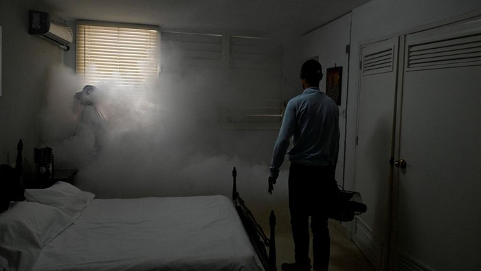State worker Carlos Gutierrez uses a fogging machine to fumigate inside a house, beside an image of late revolutionary hero Che Guevara as part of a public health campaign against the spread of mosquito-transmitted virus that causes Chikungunya, in Havana, Cuba November 13, 2025. REUTERS/Norlys Perez