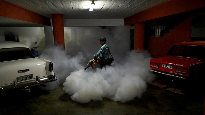 State worker Carlos Gutierrez uses a fogging machine to fumigate inside a house, beside an image of late revolutionary hero Che Guevara as part of a public health campaign against the spread of mosquito-transmitted virus that causes Chikungunya, in Havana, Cuba November 13, 2025. REUTERS/Norlys Perez