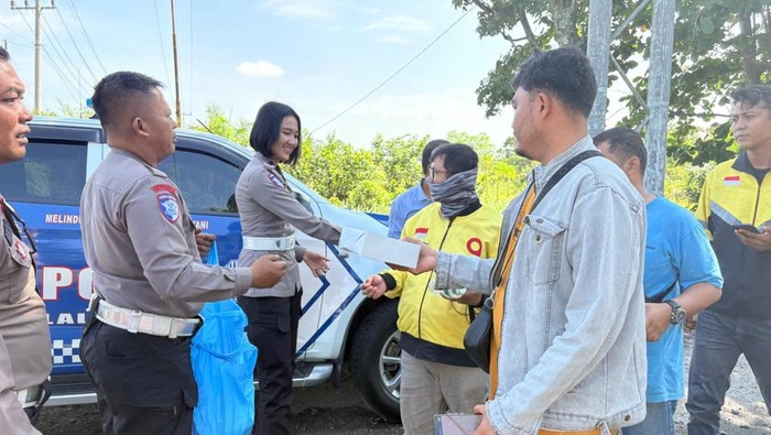 Polantas Polda Riau membagikan makanan sambil sosialisasi Operasi Zebra Lancang Kuning 2025.
