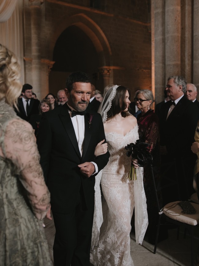 Wanita 25 tahun itu mengenakan gaun renda off-the-shoulder dengan kerudung katedral panjang yang menjuntai di belakangnya. Gaun itu berdesain abadi dengan hiasan renda yang rumit tapi memberi kesan romantis dan klasik. Foto: Instagram @melaniegriffith