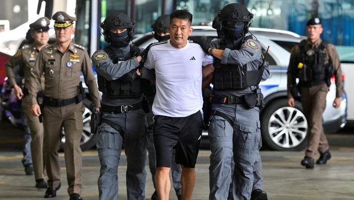 She Zhijiang, 43, a Chinese national gambling kingpin who was arrested by Thai police in August 2022 on an international warrant and an Interpol red notice requested by Beijing of having run illegal online gambling operations, is escorted by police ahead of being extradited to China, at Bangkok Suvarnabhumi Airport, in Samut Prakan, Thailand, November 12, 2025. REUTERS/Thanaphon Wuttison     TPX IMAGES OF THE DAY
