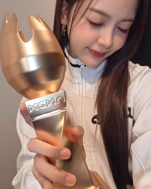 Carmen Hearts2Hearts memamerkan piala KGMA 2025. Dia menang di  kategori Trend of the Year (Rookie).