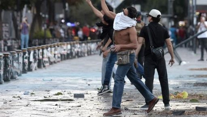 Demonstrators throw stones towards the Jalisco State Government Palace during clashes at a rally against the government of Mexicos President Claudia Sheinbaum in Guadalajara, Jalisco state, Mexico on November 15, 2025. Thousands of people marched through the streets of Mexico City on Saturday to protest against drug violence and the security policies of President Claudia Sheinbaums government. (Photo by ULISES RUIZ / AFP)