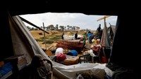 Di atas tenda berlumpur, pengungsi terlihat sigap menahan tiang dan menambal kain yang robek, berjuang mempertahankan atap yang menahan dingin dan basahnya hujan. REUTERS/Mahmoud Issa
