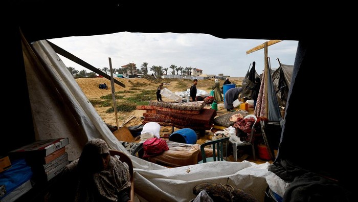 Hujan deras dan angin kencang yang melanda Jalur Gaza bagian tengah, Minggu (16/11/2025), kembali menambah kesulitan bagi para pengungsi Palestina. Tenda-tenda yang menjadi tempat tinggal sementara mereka rusak diterjang cuaca buruk, memaksa warga untuk bertahan dan segera melakukan perbaikan di tengah hujan yang tak henti. REUTERS/Mahmoud Issa