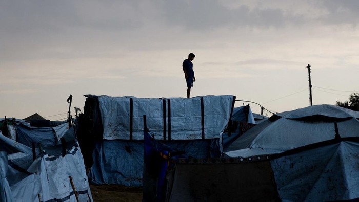 Hujan deras dan angin kencang yang melanda Jalur Gaza bagian tengah, Minggu (16/11/2025), kembali menambah kesulitan bagi para pengungsi Palestina. Tenda-tenda yang menjadi tempat tinggal sementara mereka rusak diterjang cuaca buruk, memaksa warga untuk bertahan dan segera melakukan perbaikan di tengah hujan yang tak henti. REUTERS/Mahmoud Issa