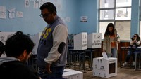 Seorang perempuan memberikan suara dalam referendum untuk memutuskan apakah akan mengizinkan kembalinya pangkalan militer asing dan apakah mereka mendukung pembentukan majelis untuk menulis ulang konstitusi, di sebuah stasiun pengumpulan di Quito, Ekuador, Minggu (16/11/2025). REUTERS/Karen Toro