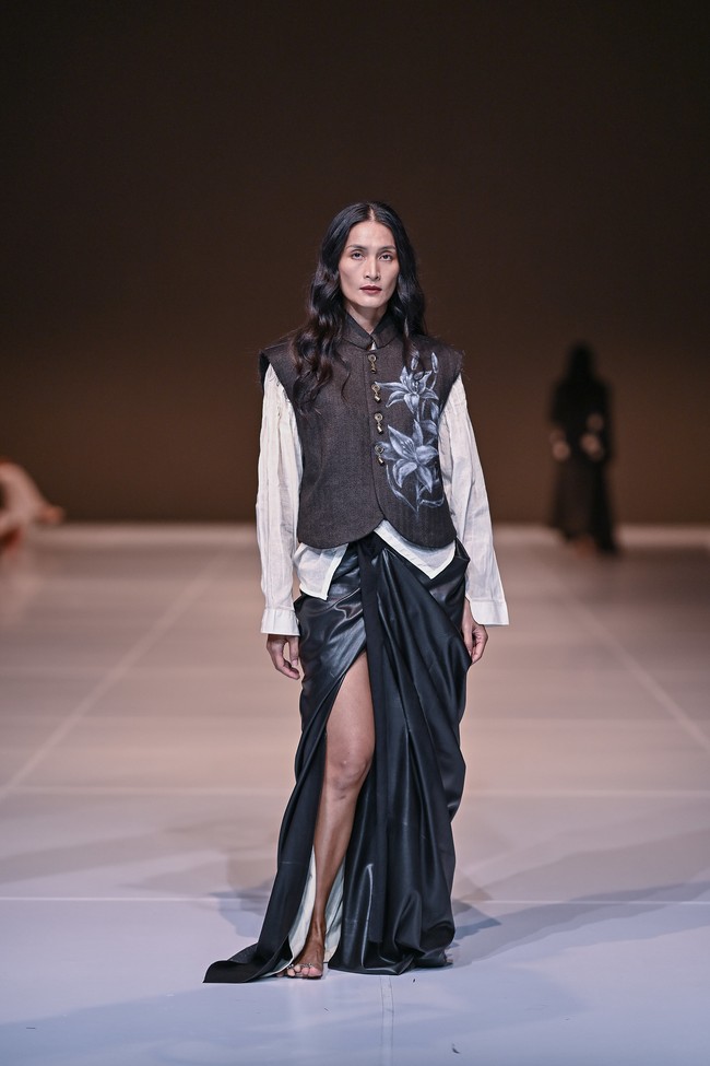 Koleksi ini menggabungkan kain tenun tangan dengan rok panjang drapery signature mereka, paduan yang menciptakan kontras antara ketegangan dan ketenangan. Draping lembut mengalir mengikuti kontur tubuh, sementara tekstur tenun memberikan bobot visual dan kedalaman. (Foto: Dok. JFW)