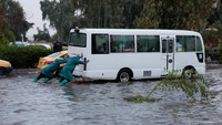 Sejumlah petugas tampak mendorong sebuah bus yang terdampar di tengah banjir, di Mosul, Irak, dan  berusaha mengarahkannya ke tempat yang lebih aman.REUTERS/Khalid Al-Mousily