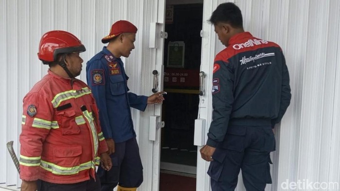 Petugas Damkar Ciamis sedang berusaha membuka rolling door minimarket yang macet.