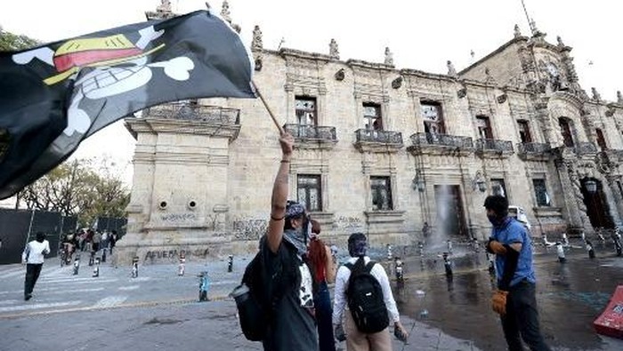 A demonstrator waves a One Piece manga flag at a rally against the government of Mexicos President Claudia Sheinbaum in Guadalajara, Jalisco state, Mexico on November 15, 2025. Thousands of people marched through the streets of Mexico City on Saturday to protest against drug violence and the security policies of President Claudia Sheinbaums government. (Photo by ULISES RUIZ / AFP)