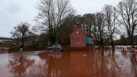 Seseorang melintasi area yang masih tergenang setelah banjir parah akibat Badai Claudia di Monmouth, Wales, Minggu (16/11/2025). Wilayah tersebut masih dalam proses pembersihan menyusul surutnya air. REUTERS/Isabel Infantes